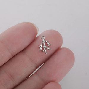 Vue macro d'un mini pendentif corail en acier inoxydable argenté sur le bout du doigt