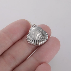 Gros plan détaillé d'un pendentif en forme de coquille d'argent montrant la taille réelle