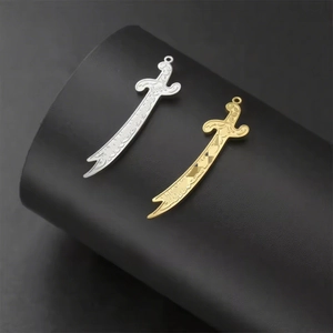 Macro shot of gold and silver sword pendants with intricate engravings on a black stand