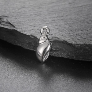 Détail macro d'un pendentif en forme de conque en acier poli sur fond d'ardoise noire