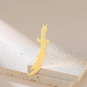 Gold sword pendant in Persian curved scimitar style on beige travertine display base