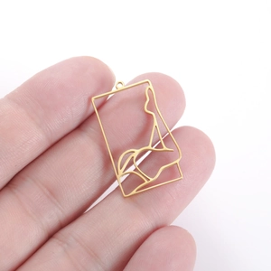 Macro shot of gold hollowed-out rectangular pendant featuring an artistic female silhouette