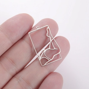 Macro shot of silver rectangular pendant with hollow female silhouette art in hand