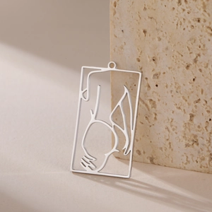 Detailed macro of a hollow rectangle pendant with artistic female silhouette on travertine