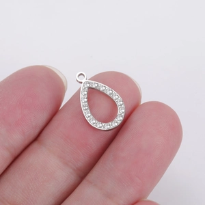 Detailed close-up of a silver teardrop pendant with micro-pave crystals held by hand