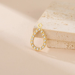 Detail of a gold teardrop pendant with micro-set zircons on a natural stone base