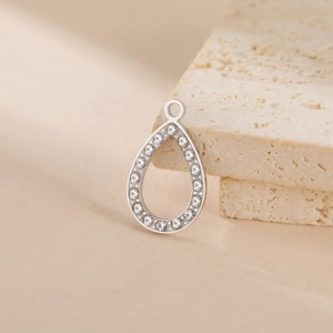 Macro view of teardrop pendant with sparkling stones on beige travertine stone surface