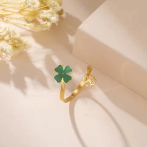Detail of adjustable gold ring featuring green enamel and hollow clover charms