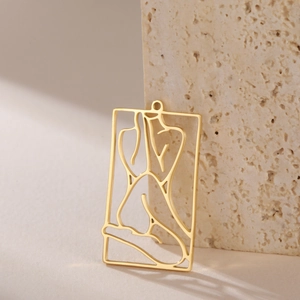 Detailed macro view of a golden hollow rectangular pendant with artistic female silhouette