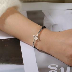 Detailaufnahme des keltischen Knotens am schwarzen geflochtenen Armband am Handgelenk