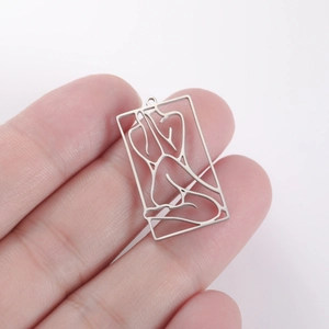 Macro detail of silver rectangular pendant featuring a minimalist hollow female silhouette