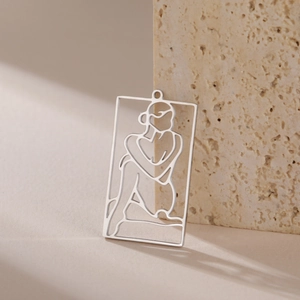 Macro detail of rectangle cutout pendant with female line art on stone