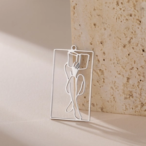 Close-up of polished stainless steel hollow rectangle pendant with artistic figure on stone
