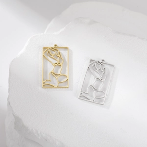 Detailed view of hollow rectangle lady pendants in gold and silver on white stone