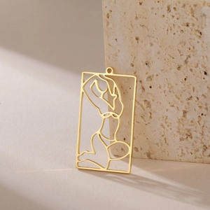 Macro shot of rectangular hollowed gold pendant with minimalist female silhouette detail