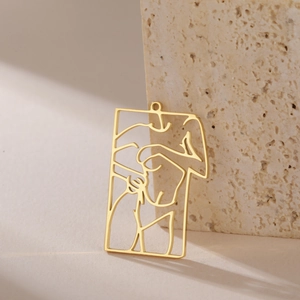 Detailed view of a gold hollow rectangular pendant with minimalist female body line art