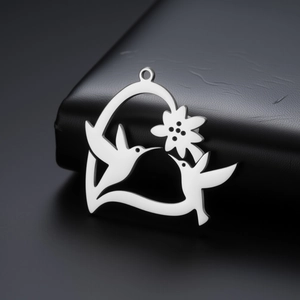 Macro d'un pendentif ajouré en acier inoxydable avec colibris et fleurs sur cuir