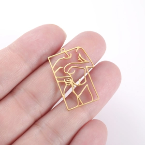Detail of a hollow gold rectangle pendant held to show size and artistic female silhouette
