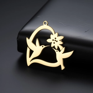 Vue détaillée du pendentif cœur doré avec colibris évidés et motif floral chic