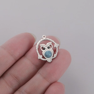 Detailed view of an owl pendant with turquoise inlay and silver stainless steel finish