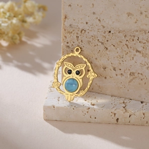 Detailed view of owl pendant with blue turquoise stone inlay on a rustic stone background