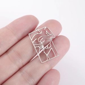 Macro shot of rectangular hollowed-out pendant featuring abstract line art of a couple