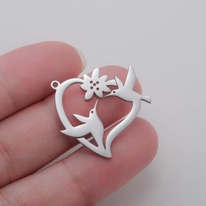 Détail du pendentif cœur colibri ajouré tenu en main pour montrer la taille et le fini