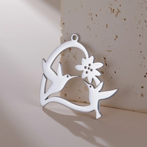 Pendentif colibri et fleur en acier inoxydable poli sur fond de pierre minimaliste
