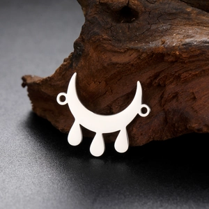 Polished stainless steel crescent moon and teardrop pendant on natural wood background