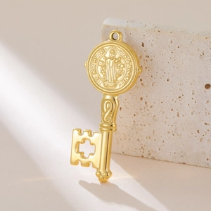 Detailweergave van een gouden St. Benedictus medaille sleutelhanger op travertijnsteen