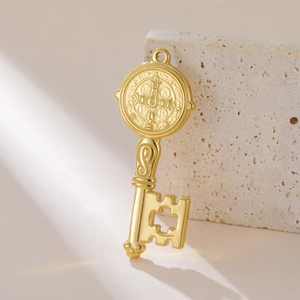 Detail van een gouden Sint-Benedictus sleutelhanger met kruisuitsparing op steen