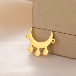 Golden crescent moon pendant with three teardrop charms on champagne satin background