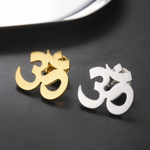 Macro shot of 18K gold and silver Om symbol pins with a polished mirror finish detail