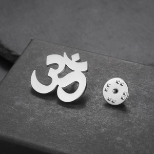 Macro detail of silver stainless steel Om yoga symbol brooch pin with butterfly clasp