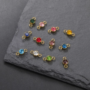 Macro detail of round birthstone charms with gold plated dual-hole connectors for DIY jewelry