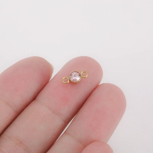 Pink birthstone connector in gold titanium steel with double loops held by hand