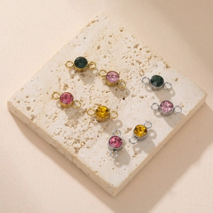 Macro detail of colorful rhinestone birthstone charms on a beige travertine stone base