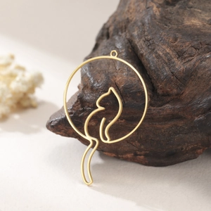 Detail of 18K gold stainless steel hollow cat pendant on dark wood and dry flower decor