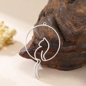 Macro detail of a silver cat silhouette charm on a textured wood background
