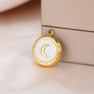 Detail of round gold pendant with moon inlay and hammered edge on silk fabric