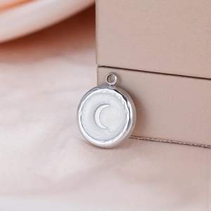 Close-up of a silver crescent moon pendant with pearl white inlay on a satin fabric