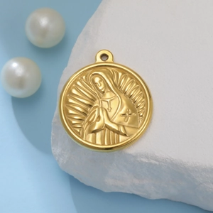 Macro shot of gold saint pendant with embossed praying figure on stone and pearl background