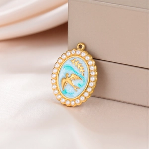 Detailed macro view of oval gold pendant with pearls, blue enamel bird and wheat ears