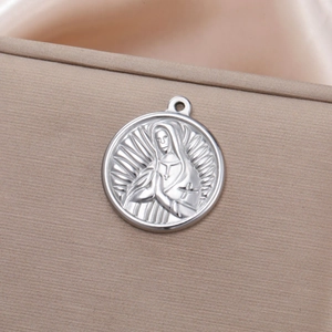 Macro shot of circular stainless steel pendant with religious praying figure relief