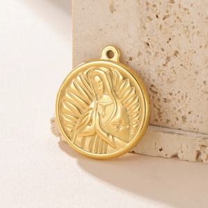 Golden round stainless steel pendant with embossed Virgin Mary on a textured stone surface