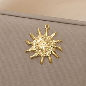 Detail eines goldenen Sonnenanhängers mit Gesichtsrelief und gewellten Sonnenstrahlen
