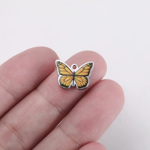 Macro view of a stainless steel butterfly pendant held by hand for scale reference