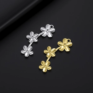 Détail macro de pendentifs à trois fleurs en acier inoxydable finitions or et argent