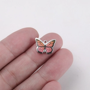 Macro shot of orange and pink gradient butterfly pendant being held to show small DIY size