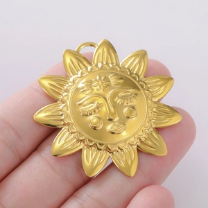 Detail eines goldenen Sonnenanhängers mit geprägtem Gesicht in der Hand gehalten